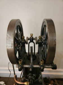Vintage mechanical press with two large iron flywheels and brass fittings. 