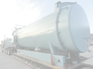 Industrial boiler mounted on a flatbed trailer, labeled 'low-emission refurbished boiler' with a website, awaiting transport or installation.