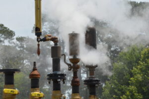 Industrial pipeline with steam vents and valves outdoors.