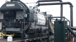 Mobile boiler plant mounted on a trailer with large black pipes and yellow gas line in an industrial setting, Cleaver-Brooks branding visible on the front