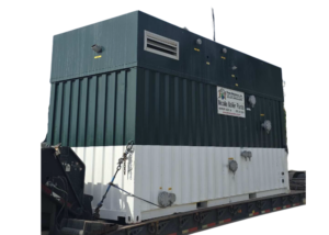 Large blue industrial boiler on a flatbed trailer with a sign reading 'Mobile Boiler Plants' and attached hoses/pipes