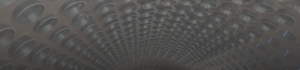 A long, curved industrial tunnel lined with rows of circular metal ducts receding into the distance, creating a tunnel-like perspective in metal tones.