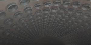 Interior of a circular tunnel with rows of metal rings receding into the distance, creating a repeating pattern