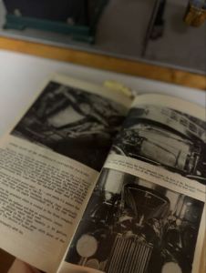 Open vintage car book showing black-and-white photos of classic automobiles on both pages, one page slightly turned.