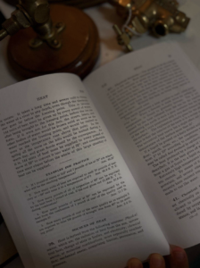 Open book with a page header 'HEAT' and dense text, held by a finger at the bottom corner.