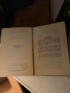 Open vintage book with a Foreword on the right page and a mirrored title page on the left in dim lighting