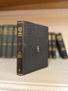 Vintage black leather-bound manual standing upright on a white shelf; spine reads Audels Engineers and Mechanics Guide, volume 7 (Pipe Fitting, Heating, Refrigeration, Elevators).