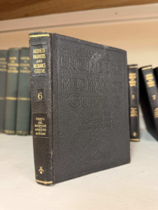 Vintage black leather-bound engineering manual on a shelf titled 'Engineer's Mechanics Guide', volume 6 on the spine.