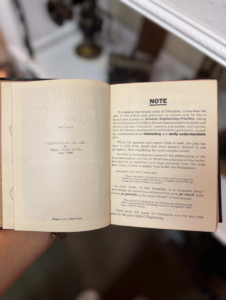 Open vintage book held at an angle, left page shows copyright information, right page titled NOTE with dense text.