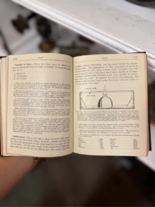 Open book held in hand, two pages about heat transfer with a small laboratory diagram.