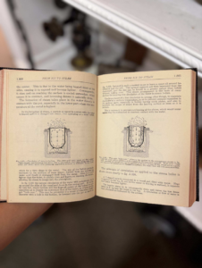 Open vintage textbook held by a hand, showing two pages with diagrams and text about steam generation/boilers.
