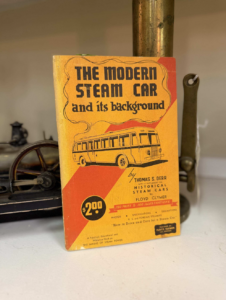 Vintage book cover: 'The Modern Steam Car and its background' with a yellow-orange background and an illustration of a bus.