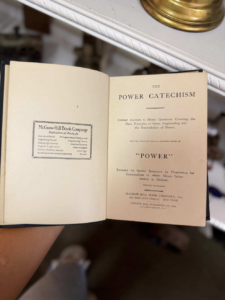 Open vintage book showing title page 'Power Catechism' on the right and a McGraw-Hill stamp on the left page.