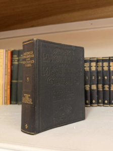 Black hardcover Audels Engineers and Mechanics Guide 8 on a shelf with other reference volumes in the background