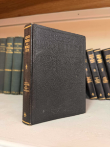 Black leather-bound hardcover book on a shelf, upright with gold text and a '4' on the spine.