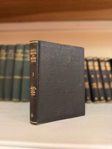 Small black vintage engineering hardcover standing on a shelf with green volumes in the background.