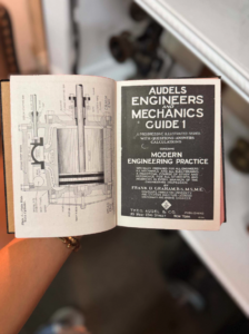 Open vintage engineering manual showing mechanical diagram on left and title page reading 'Audels Engineers and Mechanics Guide 1' on the right over a dark cover label.