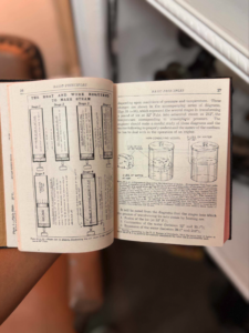 Open book showing diagrams and text about heat and work required to make steam, with labeled stages and vessels.