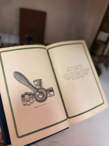 Open book showing a vintage diagram of a three-way cock valve with a lever and fittings labeled 'Three Way Cock'