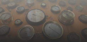 Assorted vintage analog gauges and pressure dials laid out on a wooden surface with a muted overlay.