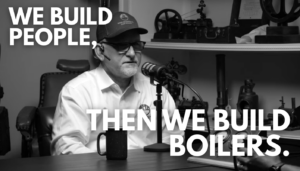Black-and-white photo of a man with a headset speaking into a microphone; overlay text reads 'WE BUILD PEOPLE, THEN WE BUILD BOILERS'.
