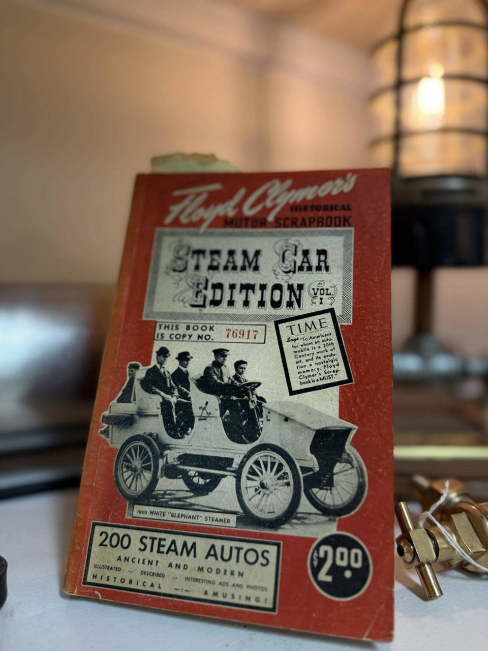 Black hardcover book titled 'Practical Treatise on the Steam Engine Indicator' resting on a table with a warm lamp glowing in the background.