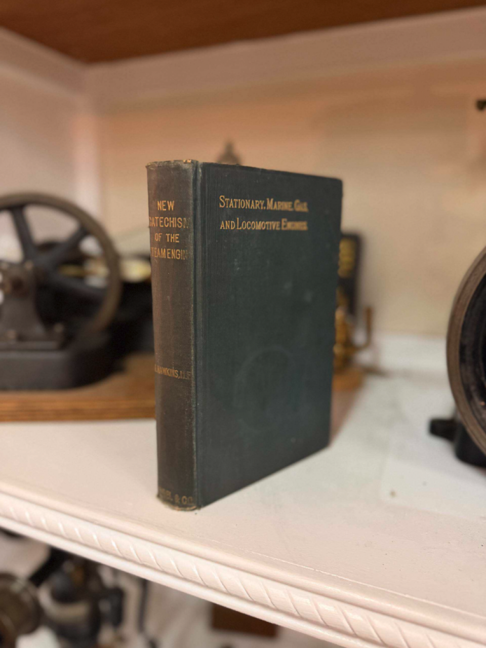 Old red hardcover book titled 'Triple Expansion Engines and Boilers' by A. Ritchie Leask, with vintage engine parts in the background.