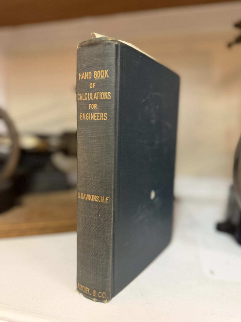 Spine of a dark blue vintage engineering book titled 'Hand Book of Calculations for Engineers' standing upright on a white surface.